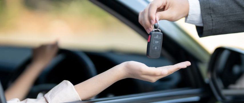 Person booking an online car rental in Pakistan on a laptop and phone through Deinfa Motors